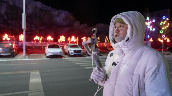 在吉林市阿什哈達霧凇觀景帶，霧凇播報員正在直播。新華社記者 李典 攝